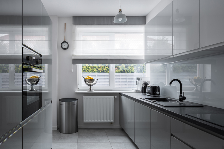 Udobna mala kuhinja sa sivim ormarićima i belim zidovima